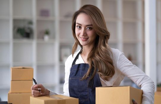 Portrait of Asian young woman SME working with a box at home the workplace.start-up small business owner, small business entrepreneur SME or freelance business online and delivery concept..