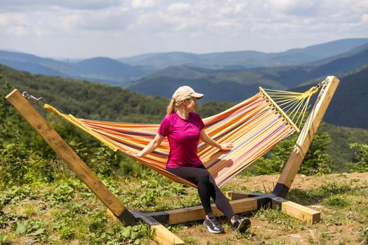 a woman rests after a hike in the mountains.