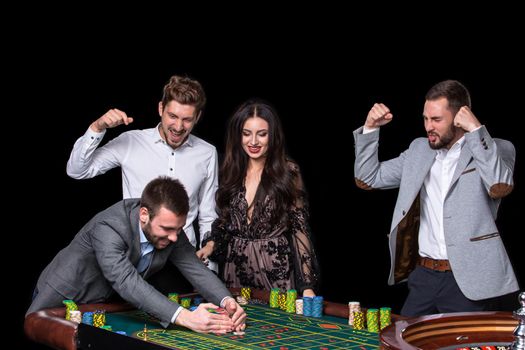 Upper class friends gambling in a casino. Roulette. Black background
