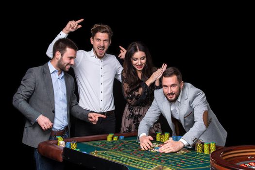 Upper class friends gambling in a casino. Roulette. Black background