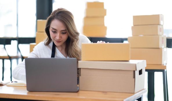 Portrait of Asian young woman SME working with a box at home the workplace.start-up small business owner, small business entrepreneur SME or freelance business online and delivery concept..