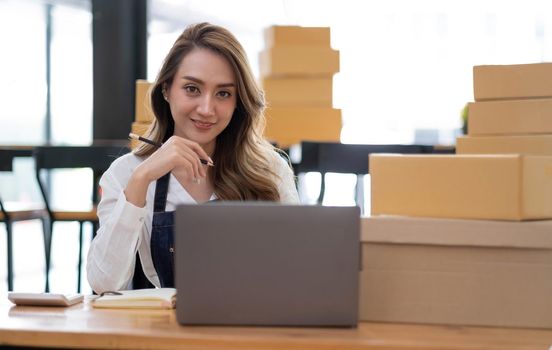 Portrait of Asian young woman SME working with a box at home the workplace.start-up small business owner, small business entrepreneur SME or freelance business online and delivery concept..