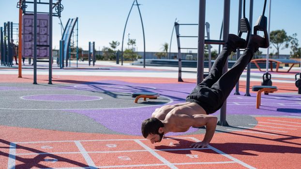 Shirtless man doing loop exercises outdoors