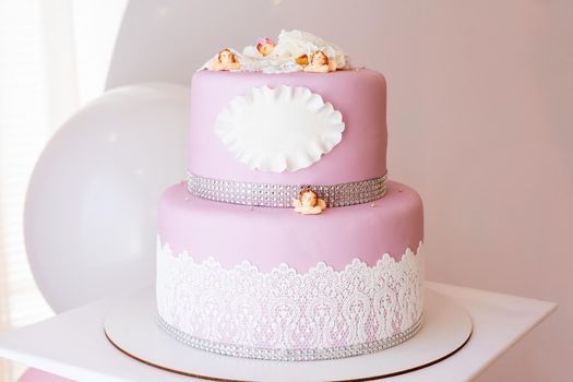 Two-tiered pink cake with a place for an inscription and little angels. Copy space.