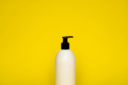 White plastic soap dispenser pump bottle isolated on yellow background. Skin care lotion. Bathing essential product. Shampoo bottle. Bath and body lotion. Fine liquid hand wash. Bathroom accessories