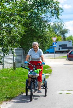 An old woman rides a bicycle. Selection focus. Nature.