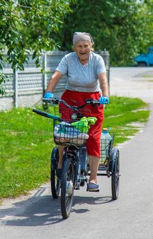 An old woman rides a bicycle. Selection focus. Nature.