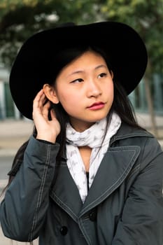 vertical portrait of a beautiful and elegant young asian woman with hat, concept of elegance and urban lifestyle