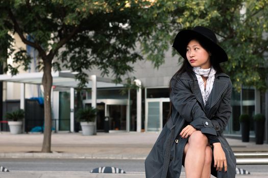 elegant asian woman sitting and waiting at the city, concept of public transportation and urban lifestyle, copyspace for text