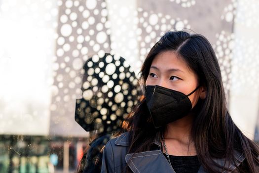 portrait of an asian woman wearing a black protective mask, concept of protection against pollution and viruses, copyspace for text