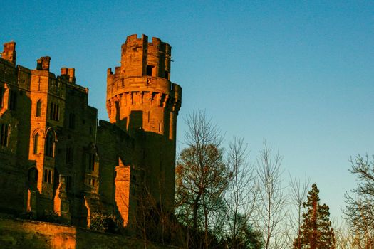 Ancient European medieval architectural building castle in golden autumn light with the blue sky background during autumn