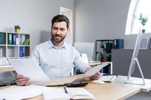 Happy businessman at paper work, examining financial documents, man at work working in the office