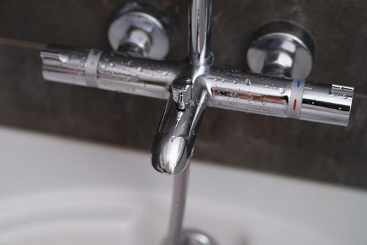 Chrome faucets on white ceramic bathtub in bathroom. Water drops on the faucet in bathroom concept