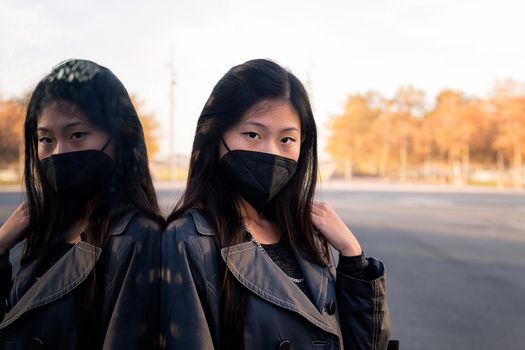 portrait of an oriental woman wearing a black protective mask reflected in a mirror, concept of protection against pollution and viruses, copyspace for text