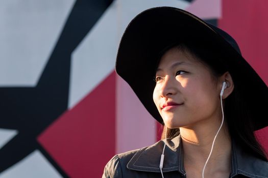 young beautiful classy chinese woman with earphones listening music, concept of technology and fashion lifestyle