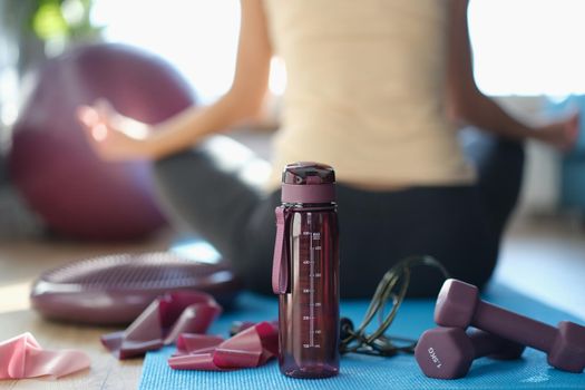 Sports set of accessories of goods for fitness and woman sits with back in lotus position. Relaxation relaxation and sports mood concept