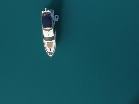 Aerial boat race. Luxury cruise trip. View from above of white boat on deep blue water. Aerial view of rich yacht sailing sea. Motor boat racing wave. Summer journey on luxury ship