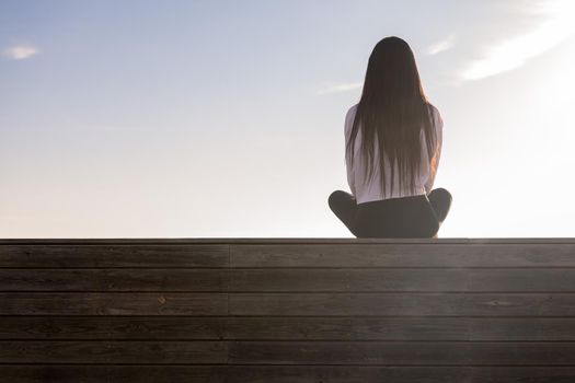 rear view of a woman with long hair meditating at sunset, concept of relaxation and mental health, copy space for text