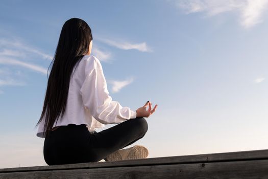 unrecognizable young woman with long hair meditating at sunrise, relaxation and mental health concept, copyspace for text