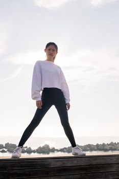 vertical photo of a powerful asian sportswoman posing confident looking at camera, concept of sport and healthy lifestyle, copyspace for text