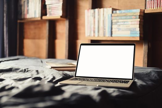 Laptop on the bed with soft light from window. White screen for your advertise text.