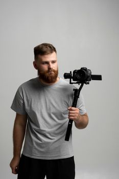 Proffesional videographer making a good footage using steadicam. Cameraman creator with a stabilizer in his hands takes a video on the slr video camera on white background. Creating a video content