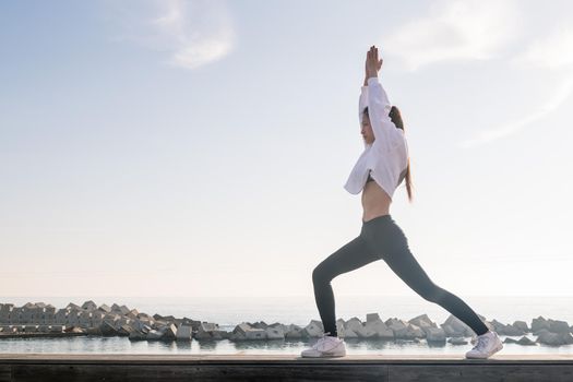 beautiful young asian woman practicing yoga in the morning near of the sea, concept of relaxation and mental health, copy space for text