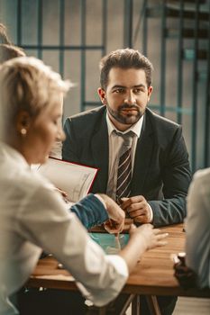 Brainstorming Of Business Team In Office, Caucasian Handsome businessman Sitting With Group Of People At Business Meeting, Selective Focus On Serious Male Face, Toned Image