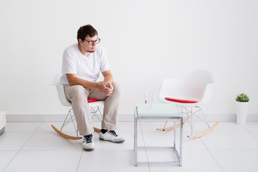 Mental health and healthcare. Young depressed man with headache sitting on the chair