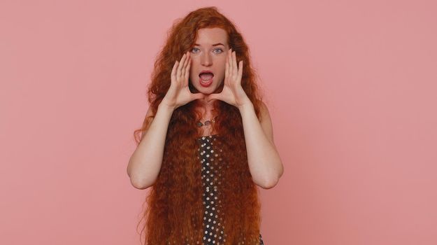 Expressive woman holding hands near mouth loudly screaming, shouting, yelling, announces discounts sale Hurry up, welcomes someone hello. Young redhead girl isolated alone on pink studio background