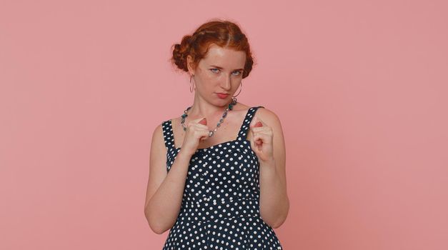 Greedy avaricious redhead young woman showing fig negative gesture, you dont get it anyway. Rapacious, avaricious, acquisitive. Body language. Refusal fig sign. Ginger girl indoor on pink background