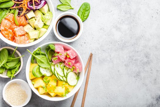 Two assorted poke bowls with raw fish and vegetables, space for text. Top view, close up. Hawaiian dish, rustic stone background. Healthy clean eating concept. Poke with raw fish slices, copy space