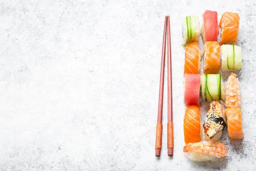 Assorted sushi set on white concrete background. Japanese sushi, chopsticks. Space for text. Top view. Sushi nigiri. Japanese dinner/lunch. Different sushi mixed. Japanese food concept. Food frame