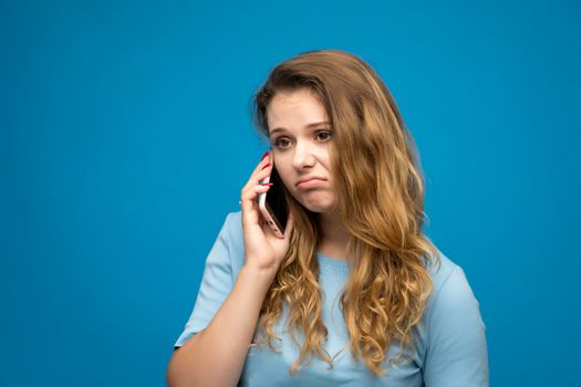 Young female feels displeased annoyed and anxious while speaking with a mobile phone