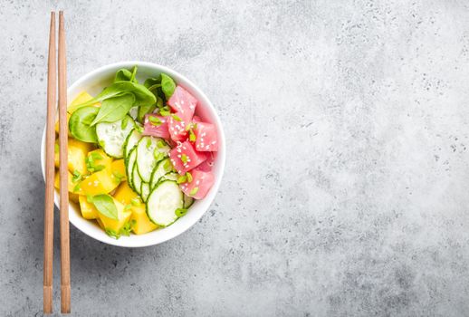 Top view of poke bowl with fresh raw tuna, fruit, vegetables, space for text. Traditional Hawaiian dish on rustic stone background. Healthy and clean eating concept. Poke with fish slices, copy space