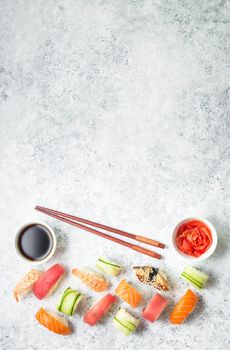 Assorted sushi set on white concrete background. Space for text. Japanese sushi, rolls, soy sauce, ginger, chopsticks. Top view. Sushi nigiri. Japanese dinner/lunch. Food frame. Different sushi mixed