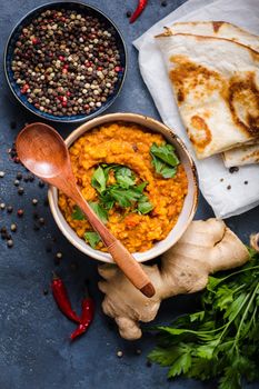 Traditional Indian lentils Dal, naan butter bread, fresh coriander. Indian Dhal spicy curry in bowl, spices, herbs, rustic concrete background. Top view. Indian food. Authentic Indian dish. Overhead