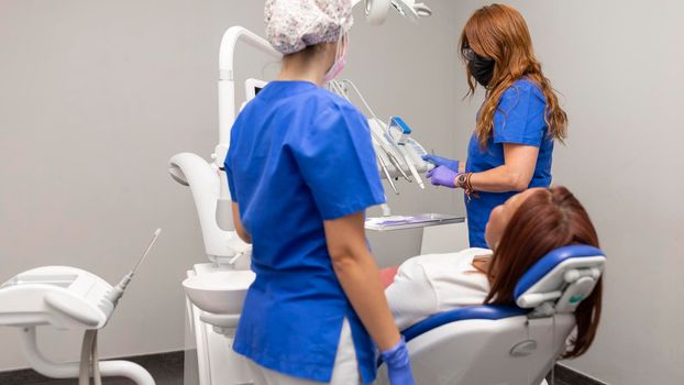 Two dentist women are about to start the dental checkup for one of her black woman clients at the dental clinic