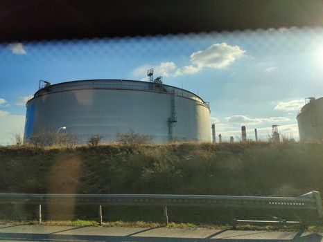 Oil storage tank terminal and tanker, petrol industrial zone shot from a moving car.