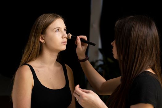 Proffesional makeup artist apply liquid tonal foundation on the face of the woman. Beauty fashion model. . Professional make up in a visage studio