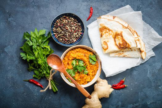 Traditional Indian lentils Dal, naan butter bread, fresh coriander. Indian Dhal spicy curry in bowl, spices, herbs, rustic concrete background. Top view. Indian food. Authentic Indian dish. Overhead