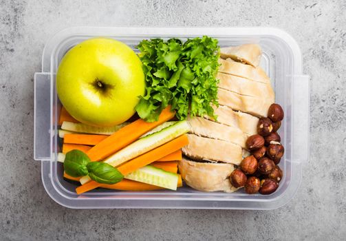 Healthy food lunchbox for office or school: chicken fillet, carrot, cucumber sticks, salad, apple. Preparation and packaging of meal to support balanced lifestyle or diet, stone background, copy space