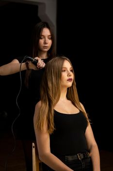 Beautiful, brunette hair girl with long hair and her hairdresser in a beauty salon. Professional hair care and creating hairstyles
