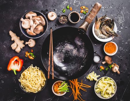 Asian food cooking concept. Empty wok pan, noodles, vegetables stir fry, shrimps, sauces, chopsticks. Asian/Chinese food. Top view. Ingredients for making Asian/Chinese dinner. Chinese noodles