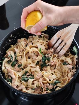 Woman squeeze a lemon on tasty home made seafood pasta in home kitchen, Closeup shot.