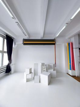 Daylight photo studio interior with set of professional equipment as a rolls of color background and white cubes on a white floor