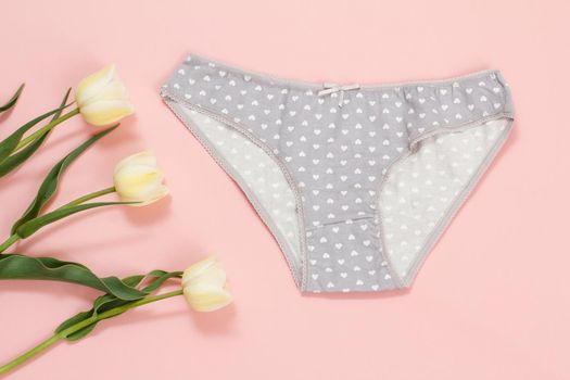 Gray cotton panties with tulip flowers on a pink background. Woman underwear set. Top view.