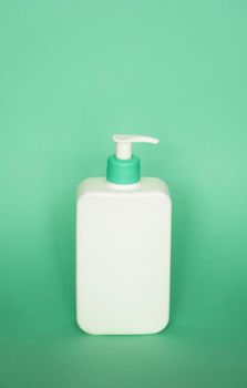 White plastic soap dispenser pump bottle isolated on green background. Skin care lotion. Bathing essential product. Shampoo bottle. Bath and body lotion. Fine liquid hand wash. Bathroom accessories