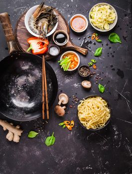 Asian food cooking concept. Empty wok pan, noodles, vegetables stir fry, shrimps, sauces, chopsticks. Asian/Chinese food. Top view. Ingredients for making Asian/Chinese dinner. Chinese noodles