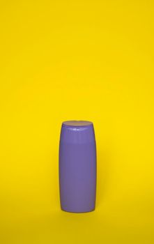 Violet plastic shampoo bottle isolated on yellow background. Skin care lotion. Bathing essential product. Shampoo bottle. Bath and body lotion. Fine liquid hand wash